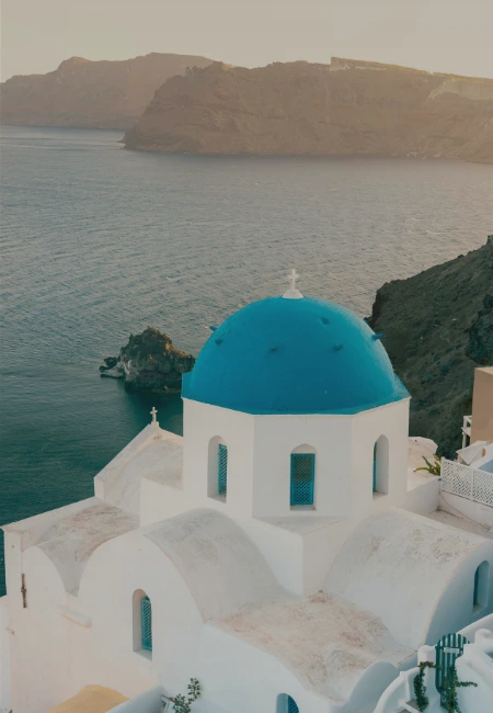 Iconic blue-domed church in Oia, Santorini, featuring traditional Cycladic architecture with a scenic view of the Aegean Sea and caldera.