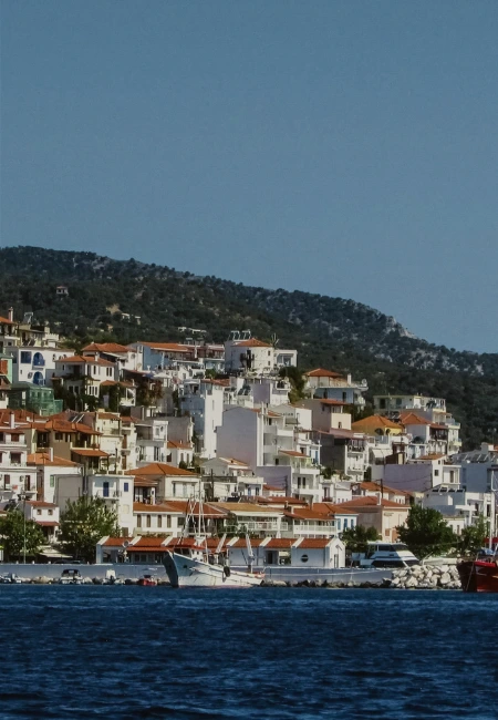 Scenic view of Skiathos Town in Greece, showcasing traditional island architecture, terracotta roofs, and a peaceful harbor on the Aegean Sea.