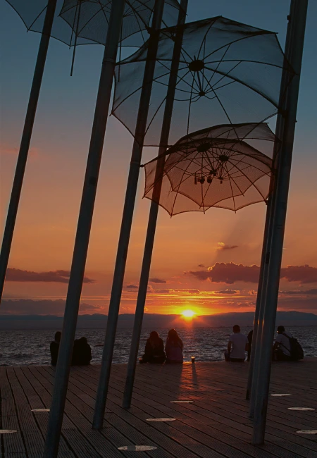 The famous Umbrellas of Zongolopoulos sculpture on the Thessaloniki waterfront in Greece during a scenic sunset.