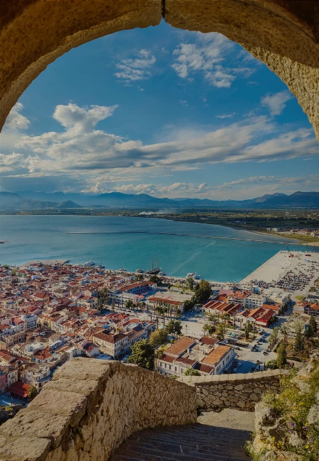 Scenic aerial view of Nafplio, Greece, from the Palamidi Fortress, showing the harbor, old town architecture, and the Argolic Gulf.